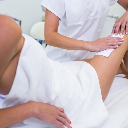 Woman getting her leg hair removed at beauty salon